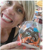 Rhonda holding a decorated cupcake wrapped in clear plastic.